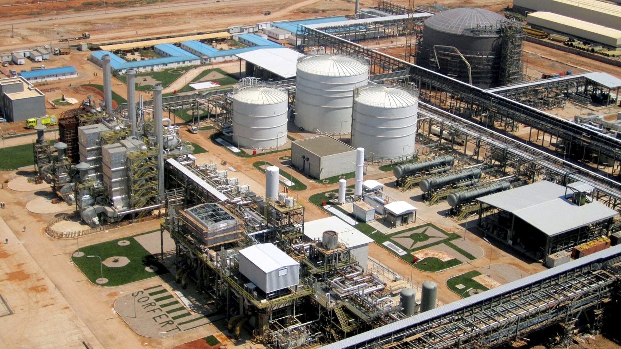 Aerial view of an ammonia and urea fertilizer complex, with three white domed storage tanks and process units